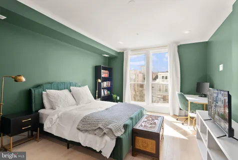 a bedroom with a bed a mirror and a flat tv screen on dresser