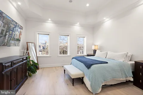 a bedroom with a large bed and dresser with window