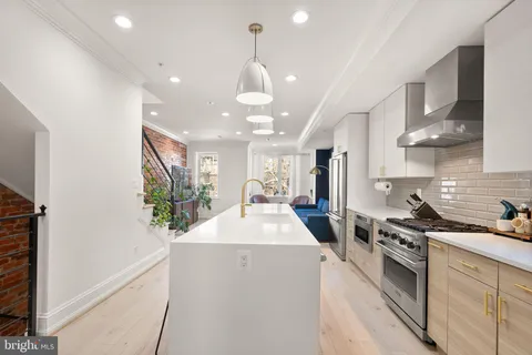 a kitchen with stainless steel appliances kitchen island a sink a stove a microwave a refrigerator and cabinets