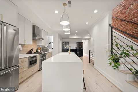 a large kitchen with kitchen island a large counter top stainless steel appliances and cabinets