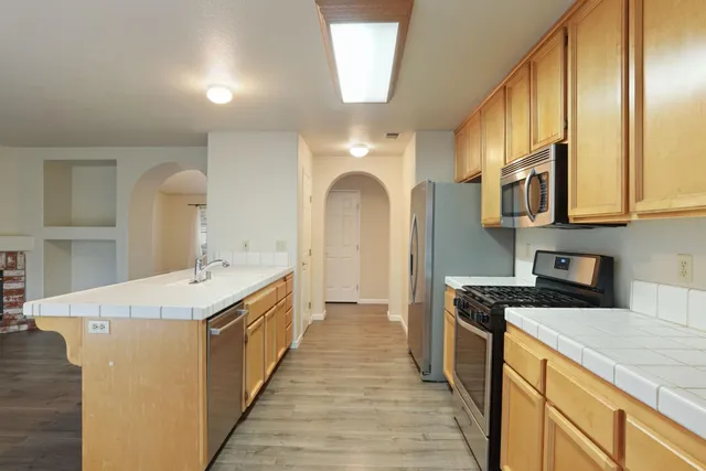 a kitchen with stainless steel appliances granite countertop a sink and dishwasher a stove top oven with wooden floor