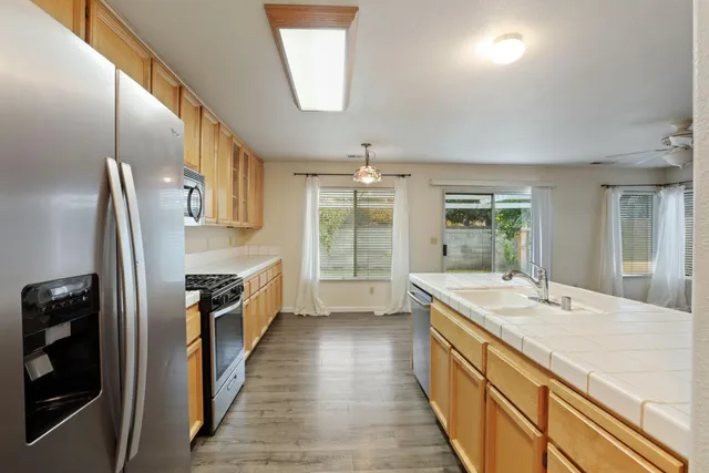 a large kitchen with stainless steel appliances a sink and large window