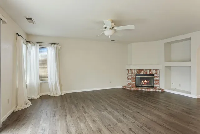 an empty room with wooden floor closet and windows