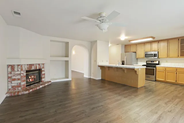 a large kitchen with stainless steel appliances a large counter top a sink a stove and a refrigerator