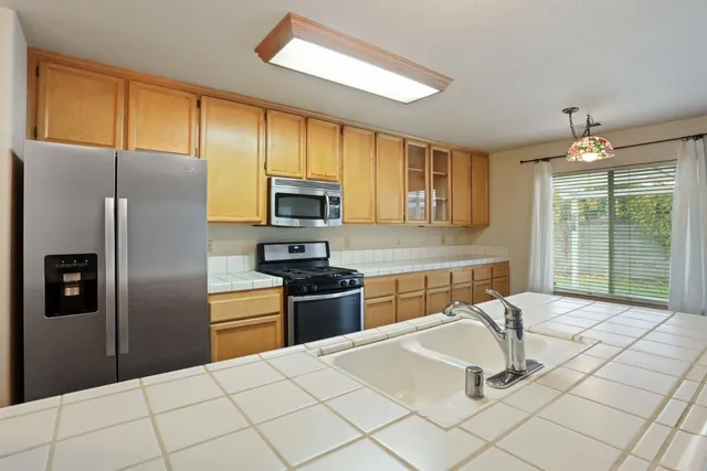 a kitchen with granite countertop a refrigerator stove top oven and sink