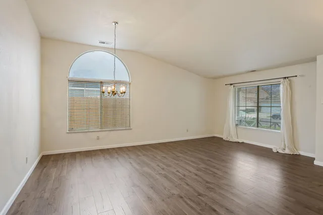 an empty room with wooden floor cabinet and windows