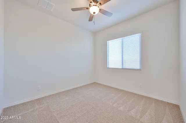 an empty room with a chandelier fan and windows