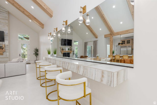 1188 South Old Trappers Loop Road Huntsville, UT 84317 - Photo 20 of 92 Expansive great room featuring a floating stone bar with pendant lighting, vaulted ceilings with exposed wood beams, a floor-to-ceiling stone fireplace, and light-tone flooring