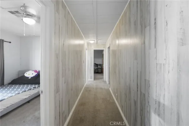 a view of a hallway with wooden floor and a bathroom