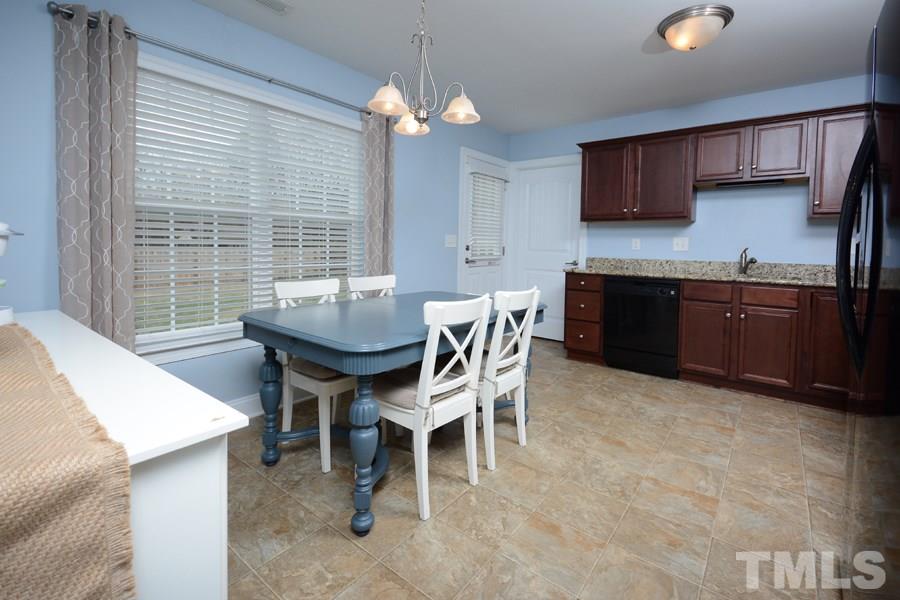 220 Orkney Road Stem, NC 27581 - Photo 5 of 18 a dining room with stainless steel appliances granite countertop a stove a sink dishwasher a dining table and chairs with wooden floor