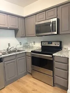 a kitchen with granite countertop a stove microwave and sink