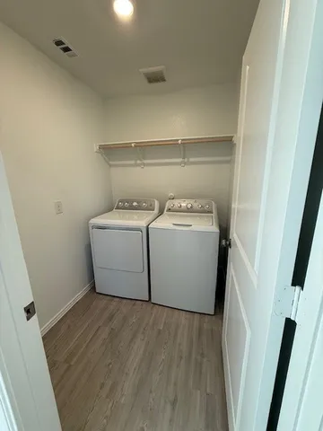 a utility room with a washer dryer and wooden floor