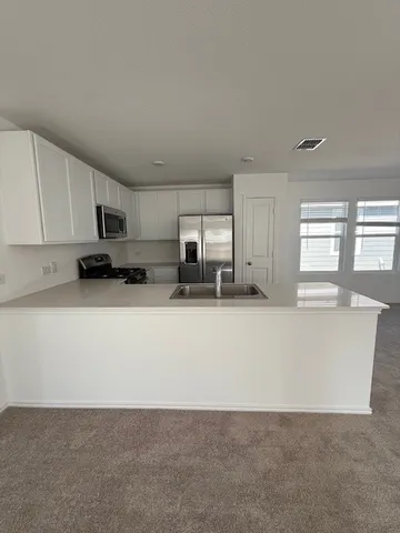 a view of kitchen with stainless steel appliances granite countertop a refrigerator a sink a stove a microwave and cabinets