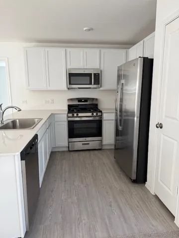 a kitchen with stainless steel appliances a refrigerator a sink a stove a microwave and wooden floors