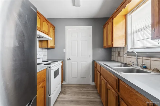 a kitchen with stainless steel appliances granite countertop a sink a stove and a refrigerator