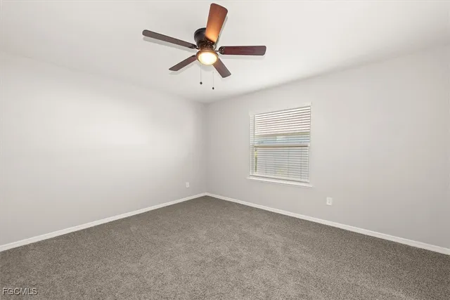 an empty room with a ceiling fan and window