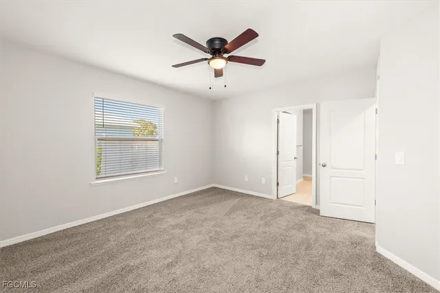 an empty room with window and ceiling fan