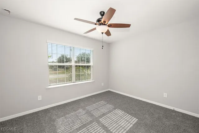 an empty room with a window and a ceiling fan