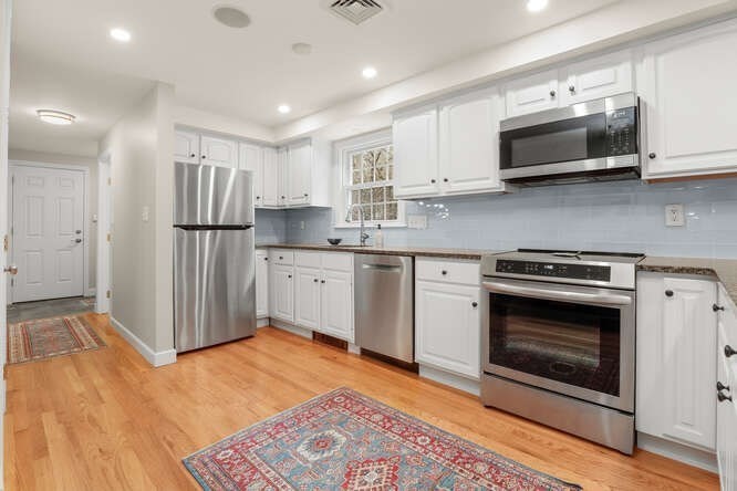 3 Summit Road Southborough, MA 01772 - Photo 6 of 41 a kitchen with stainless steel appliances granite countertop a stove top oven a refrigerator and white cabinets with wooden floor