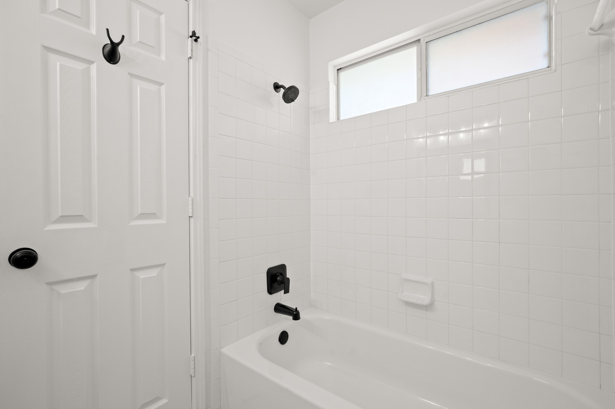 360 Sampson Kyle, TX 78640 - Photo 18 of 36 Bathtub with white subway tile surround, matte black fixtures, and an integrated soap dish