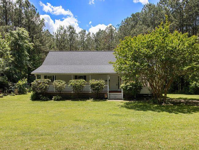 a view of house with garden and tall trees