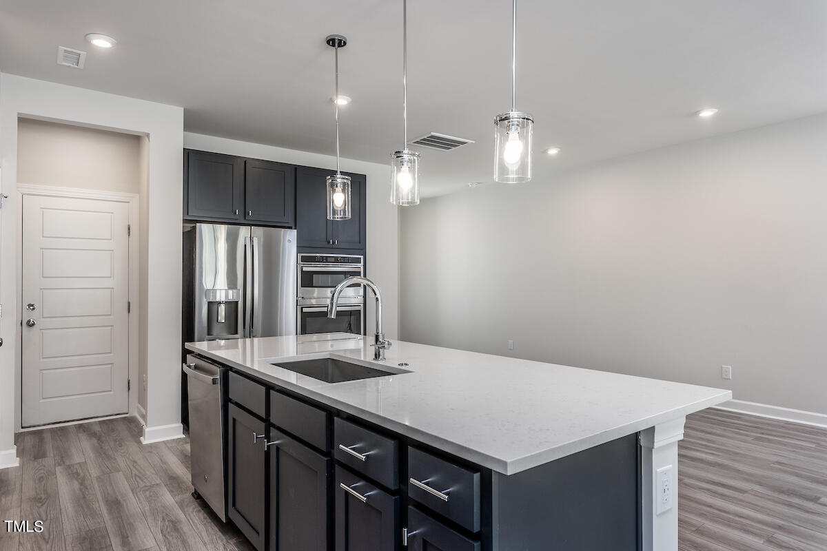 6110 Adecor Way Raleigh, NC 27617 - Photo 7 of 31 a kitchen with stainless steel appliances a kitchen island a sink dishwasher a refrigerator and wooden floor