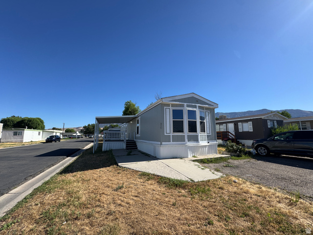 2491 Highway 89, Unit 315 Pleasant View, UT 84404 - Photo 7 of 34 Light gray exterior with white trim, featuring a bay window and a covered entry porch