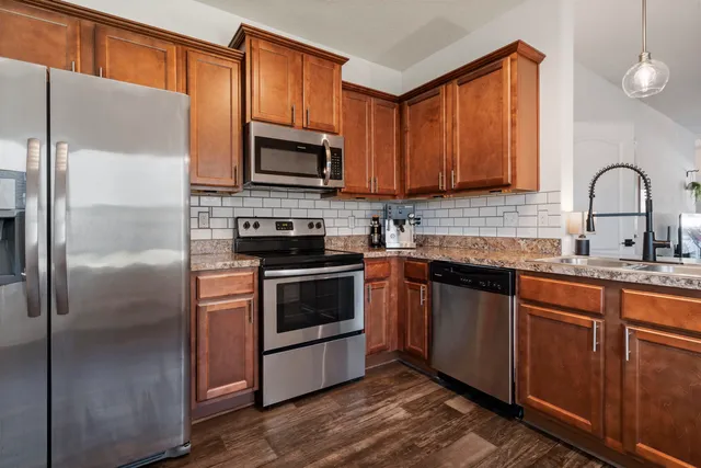 a kitchen with granite countertop a sink stainless steel appliances and cabinets