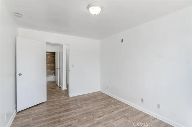 a view of an empty room with wooden floor and closet