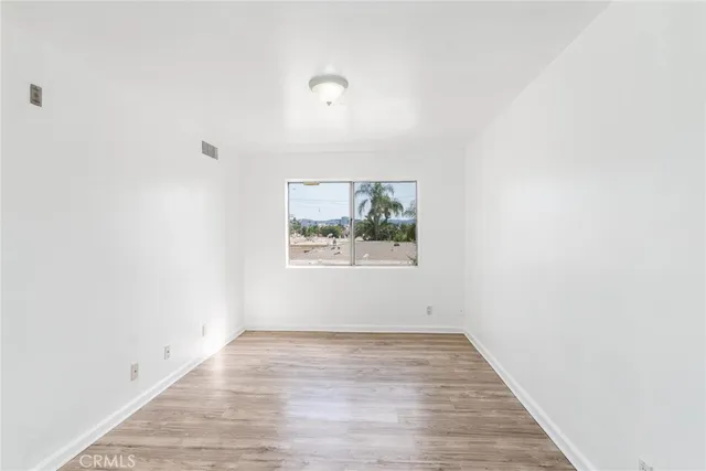 an empty room with wooden floor and window