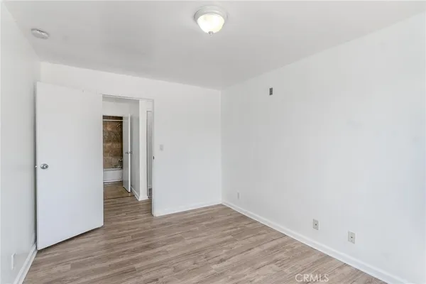a view of an empty room with wooden floor and closet