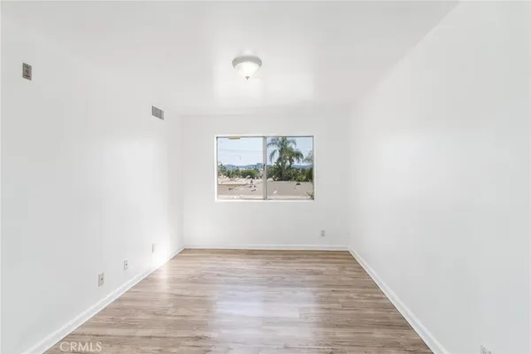 an empty room with wooden floor and window