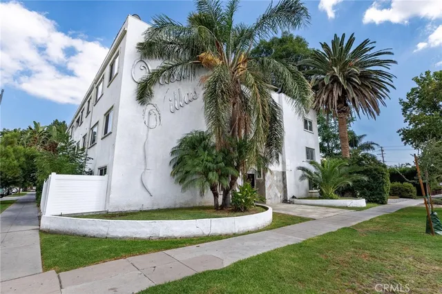 a palm tree sitting in front of a house with a yard