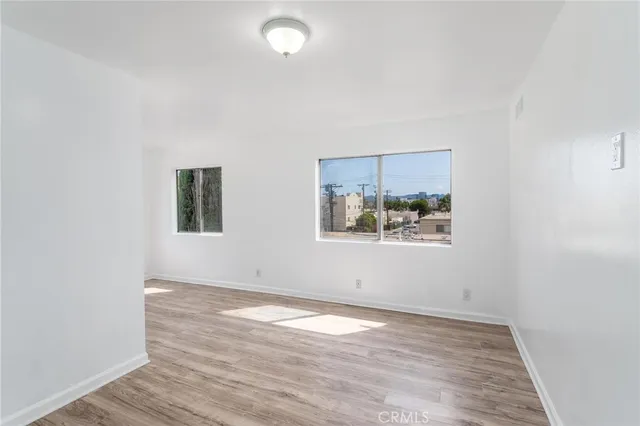 an empty room with wooden floor and window