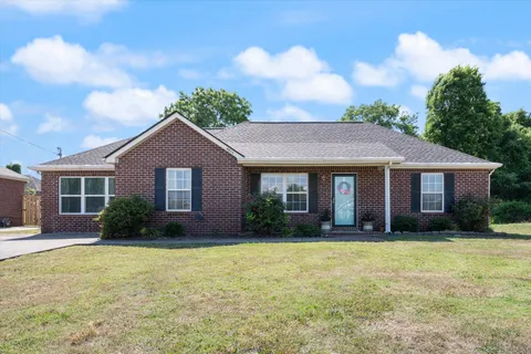 a front view of house with yard and trees in the background