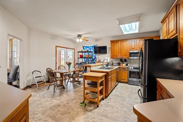 a open kitchen with stainless steel appliances kitchen island granite countertop a table chairs in it and a window