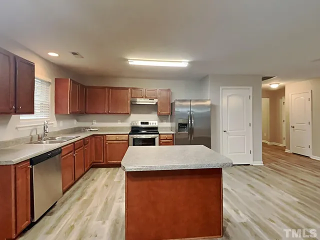 a large kitchen with stainless steel appliances kitchen island a large counter top and wooden floors