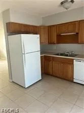a utility room with stainless steel appliances white cabinets and a refrigerator