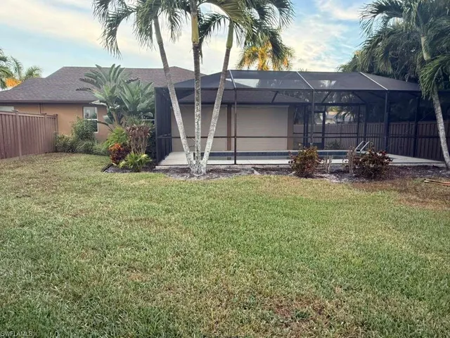 a view of a house with a yard and palm trees