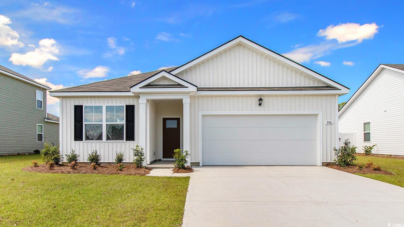 View of front of property featuring board and batten siding, an attached garage, concrete driveway, and a front yard