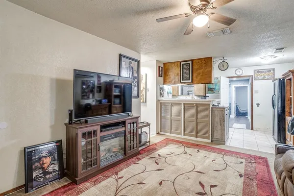 a living room with stainless steel appliances kitchen island granite countertop a stove and a flat screen tv