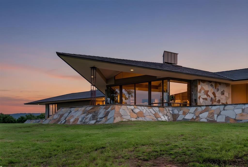 1080 North Greenbrier Road Nocona, TX 76255 - Photo 1 of 40 Modern architectural residence featuring extensive stone veneer, a distinctive cantilevered roofline, large picture windows, and a chimney stack