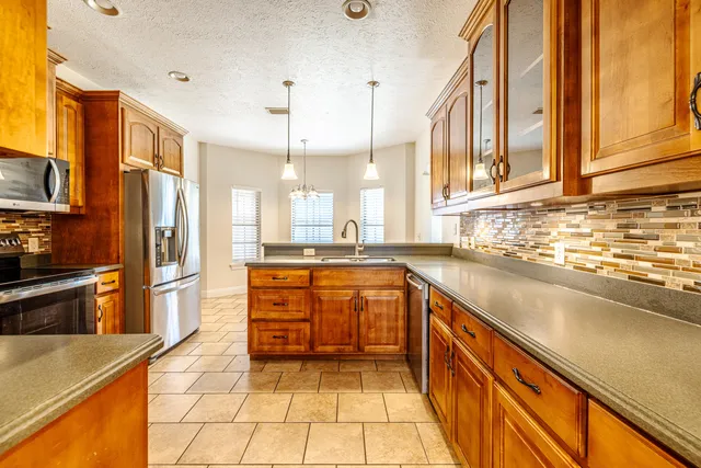a large kitchen with stainless steel appliances granite countertop a refrigerator and a sink