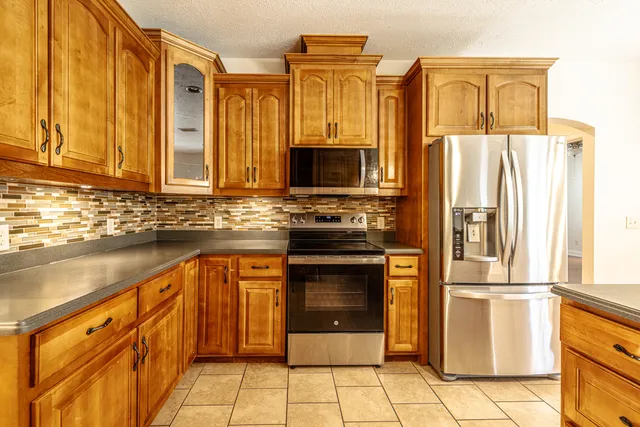 a kitchen with granite countertop a refrigerator and a stove top oven