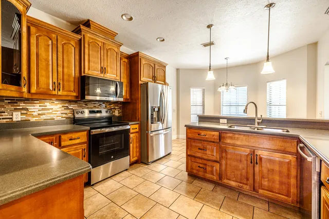 a kitchen with stainless steel appliances granite countertop a refrigerator a stove a sink and a microwave