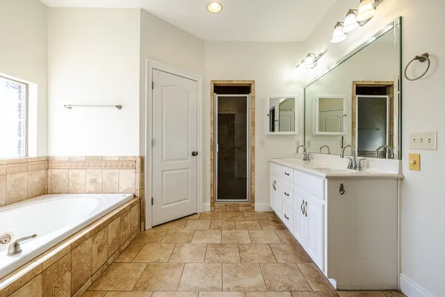 a spacious bathroom with a tub sink and mirror