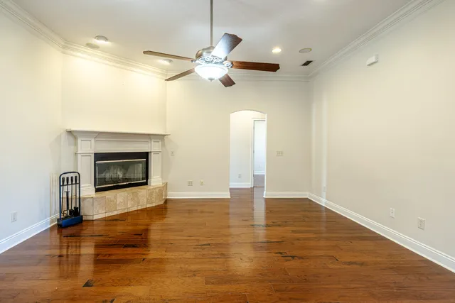 a view of an empty room with wooden floor and a fireplace
