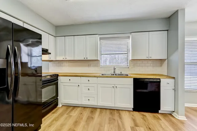 a kitchen with granite countertop a refrigerator sink and cabinets