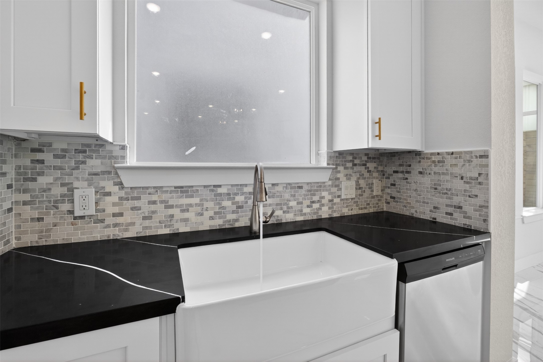 5906 St Augustine Street, Unit F Houston, TX 77021 - Photo 8 of 34 Kitchen sink area with a farmhouse-style sink, mosaic backsplash, black countertops, and dishwasher.