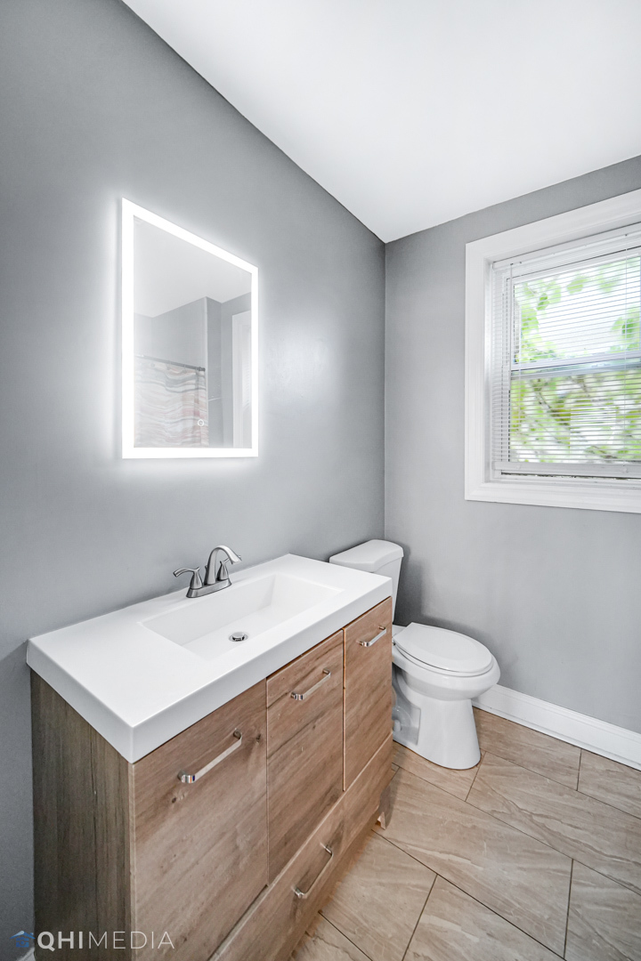 52 West 112th Street Chicago, IL 60628 - Photo 18 of 28 a bathroom with a sink mirror vanity and a toilet